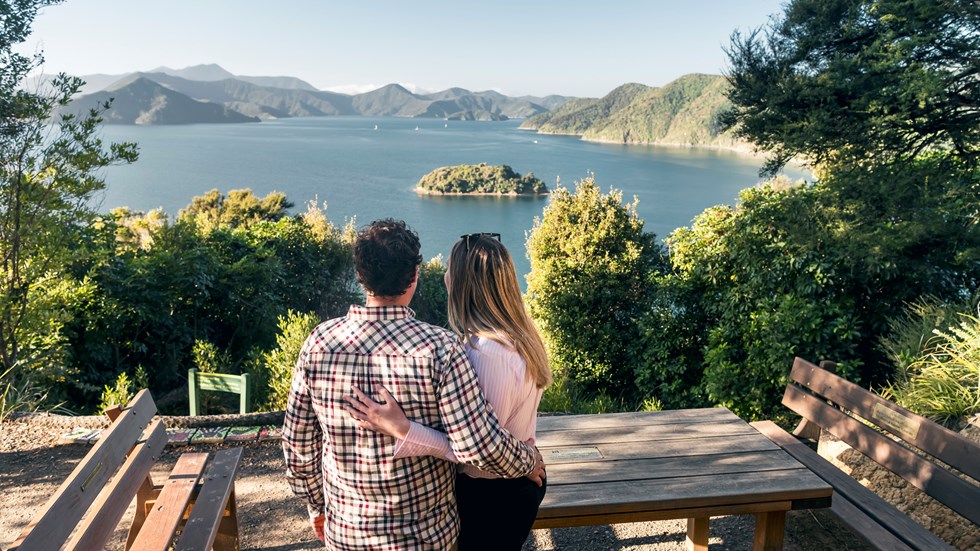 A couple look at the view over Queen Charlotte Sound/Tōtaranui from the viewpoint at Kaipupu Wildlife Sanctuary near Picton, Marlborough Sounds, New Zealand.