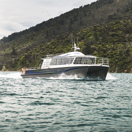 The name on the side of Cougar Line's Sounds Exciting boat sits above the boat's wake, while cruising the Marlborough Sounds, New Zealand