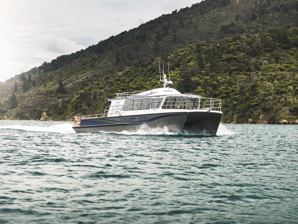 The name on the side of Cougar Line's Sounds Exciting boat sits above the boat's wake, while cruising the Marlborough Sounds, New Zealand