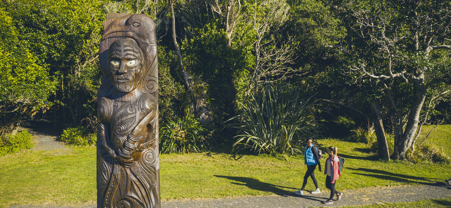 Two people walk at Ship Cove/Meretoto on the northern Queen Charlotte Track in the Marlborough Sounds, New Zealand.