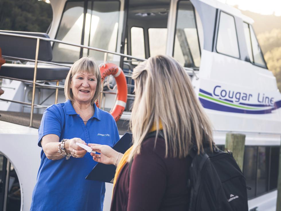 A passenger is greeted by a smiling Cougar Line staff member while boarding in Picton in the Marlborough Sounds, New Zealand.
