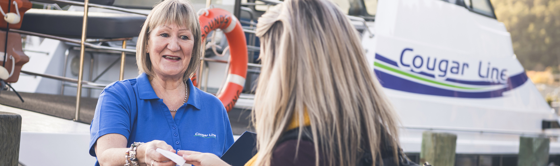 A passenger is greeted by a smiling Cougar Line staff member while boarding in Picton in the Marlborough Sounds, New Zealand.