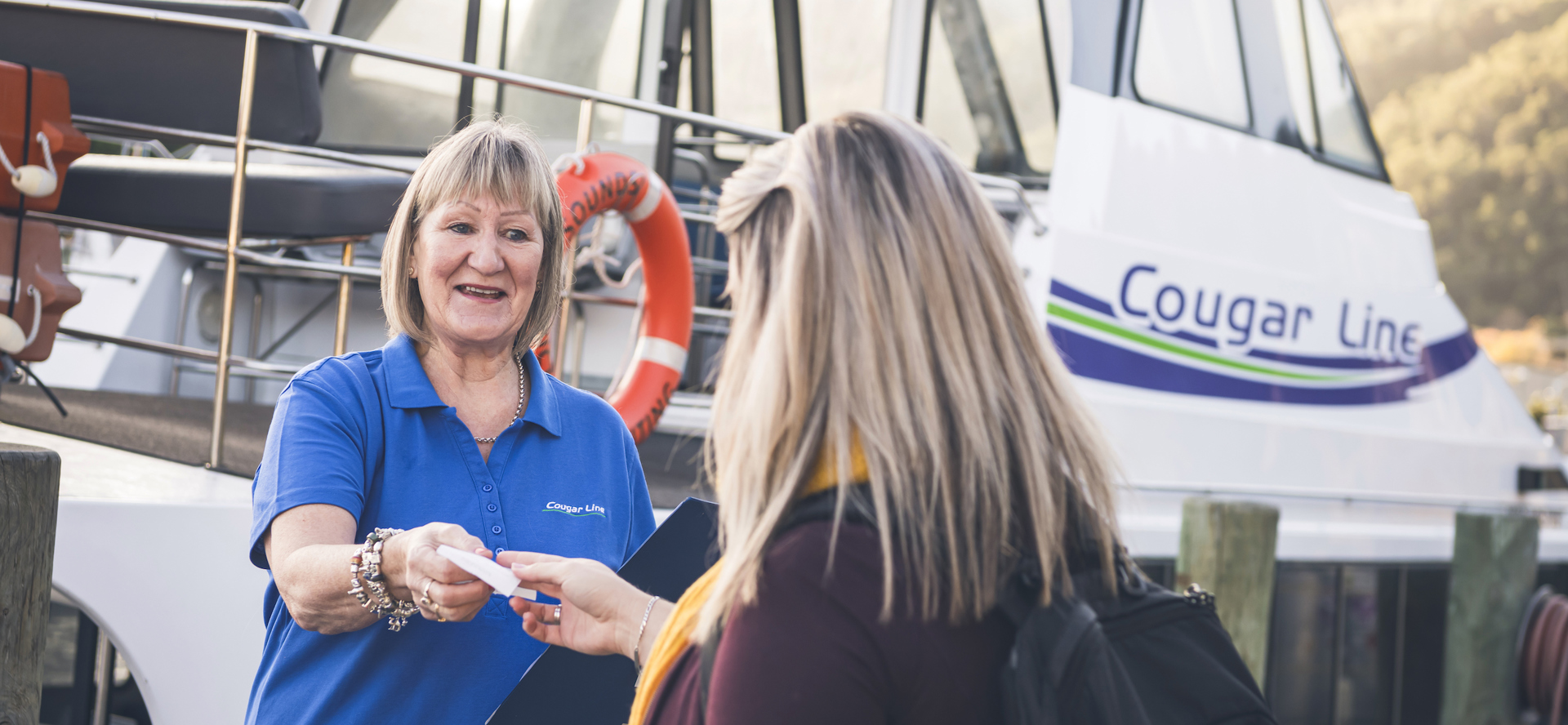 A passenger is greeted by a smiling Cougar Line staff member while boarding in Picton in the Marlborough Sounds, New Zealand.