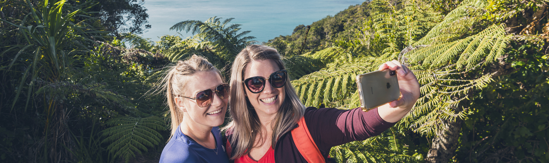 Two women take a selfie at a viewpoint on the northern Queen Charlotte Track in the Marlborough Sounds, New Zealand.