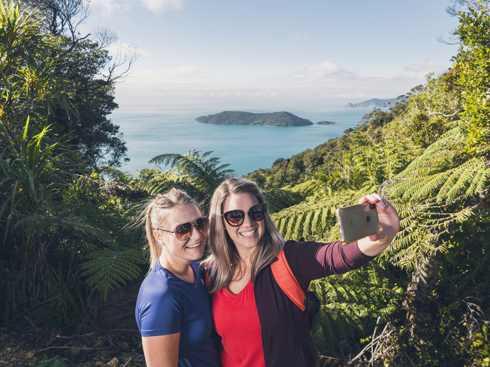 Two women take a selfie at a viewpoint on the northern Queen Charlotte Track in the Marlborough Sounds, New Zealand.