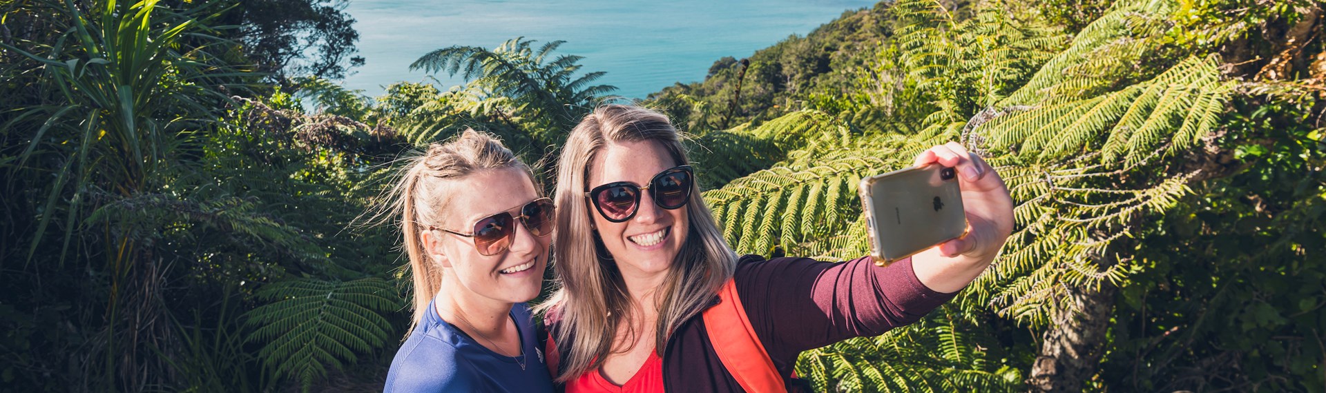 Two women take a selfie at a viewpoint on the northern Queen Charlotte Track in the Marlborough Sounds, New Zealand.