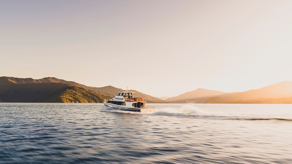 A Cougar Line boat creates a wake as it cruises into the Marlborough Sounds in the early morning, transferring passengers to the Queen Charlotte Track, New Zealand