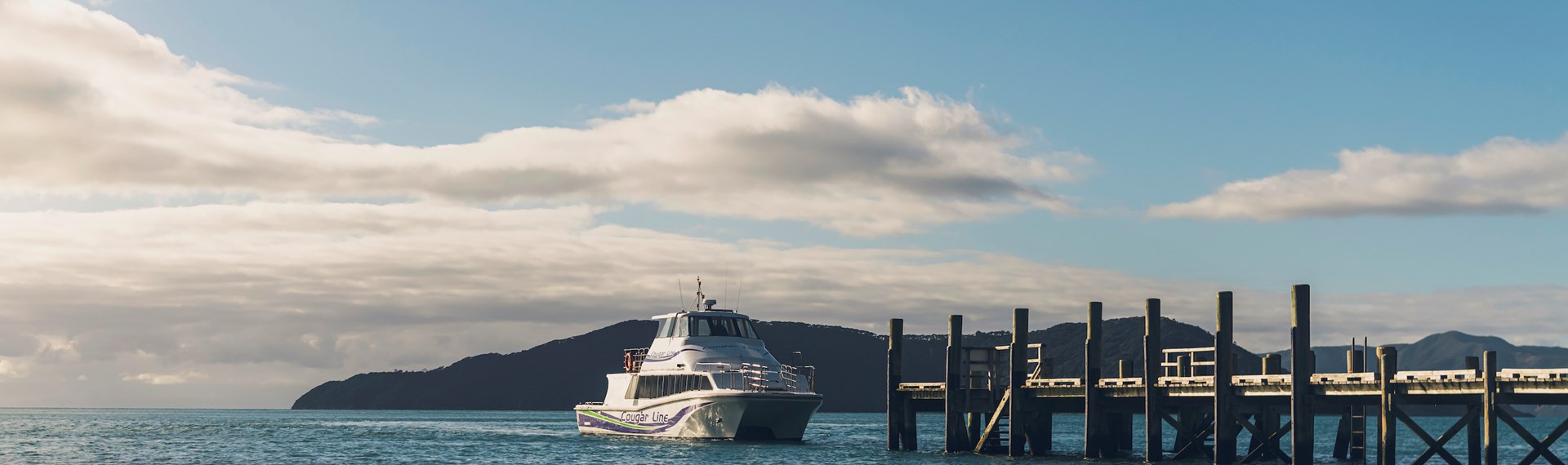 A Cougar Line boat approaches the jetty at Ship Cove/Meretoto at the start of the Queen Charlotte Track in outer Queen Charlotte Sound/Tōtaranui in the Marlborough Sounds, New Zealand..