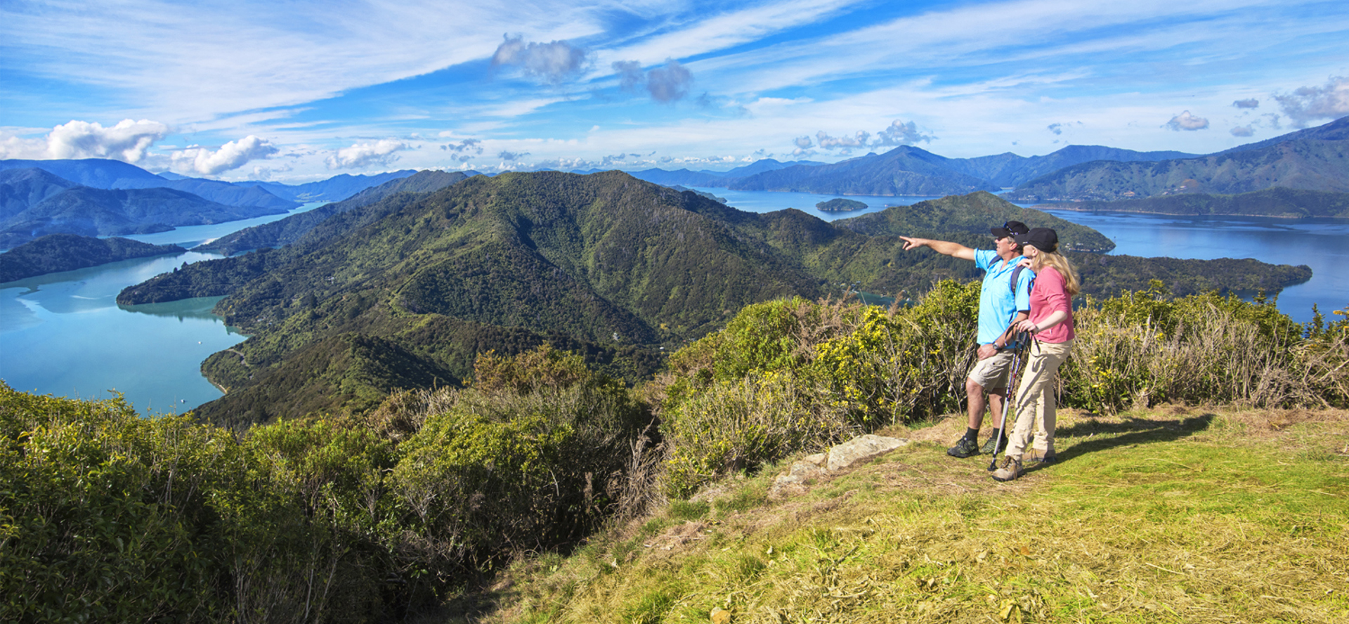 Two people walk on the northern Queen Charlotte Track in the Marlborough Sounds, New Zealand.
