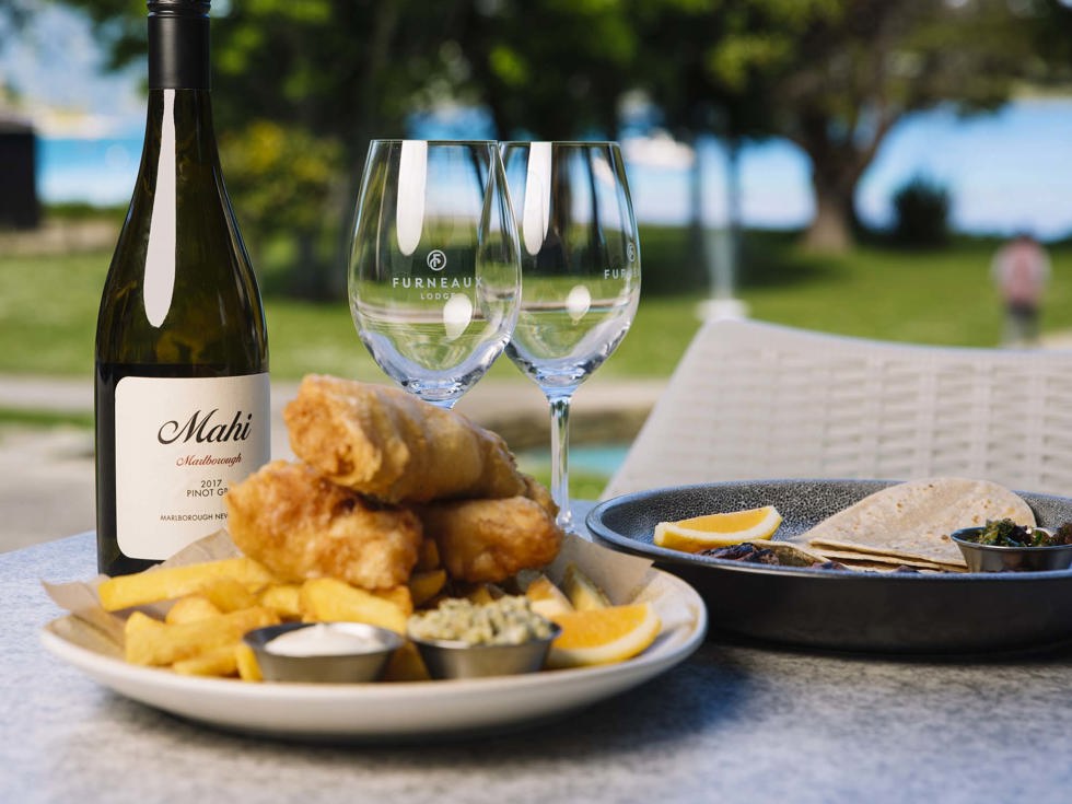 A plate of fish and chips and wine served at Furneaux Lodge in the Marlborough Sounds, New Zealand.