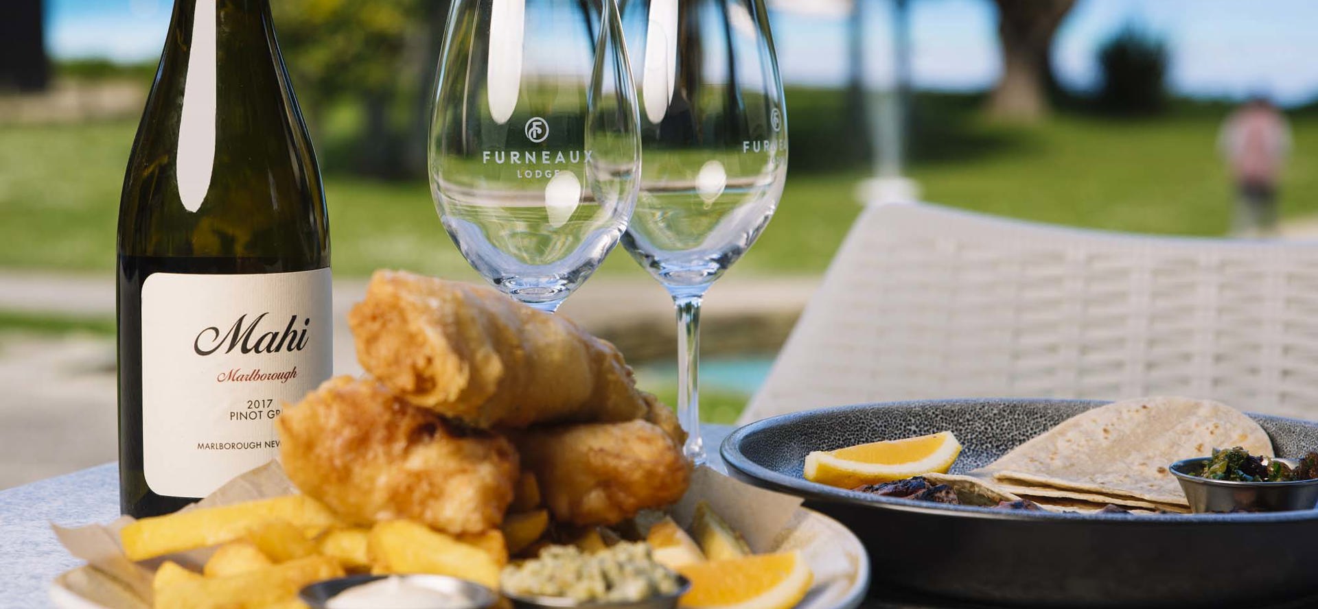 A plate of fish and chips and wine served at Furneaux Lodge in the Marlborough Sounds, New Zealand.