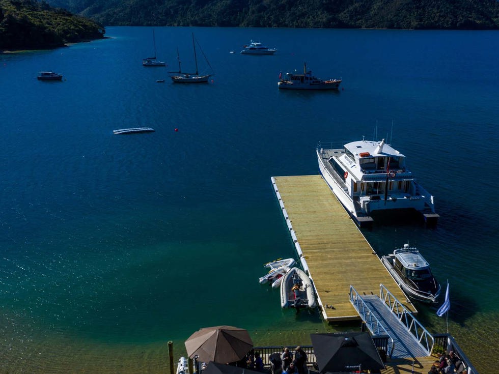 An aerial view of the Punga Cove jetty with a number of vessels parked next to it - there is also moorings available to park vessels