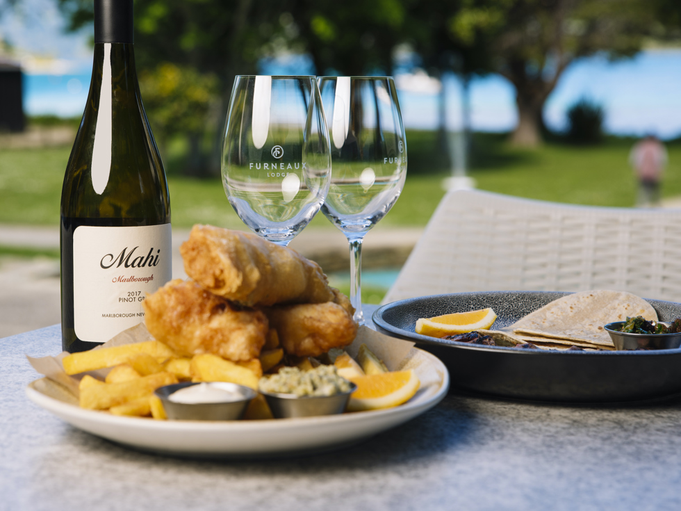 A plate of fish and chips and wine served at Furneaux Lodge in the Marlborough Sounds, New Zealand.