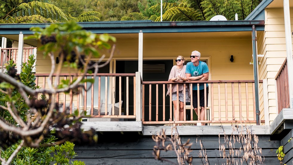 A couple stand on their room's private sun deck at Punga Cove to admire the sea view of the Marlborough Sounds, New Zealand.