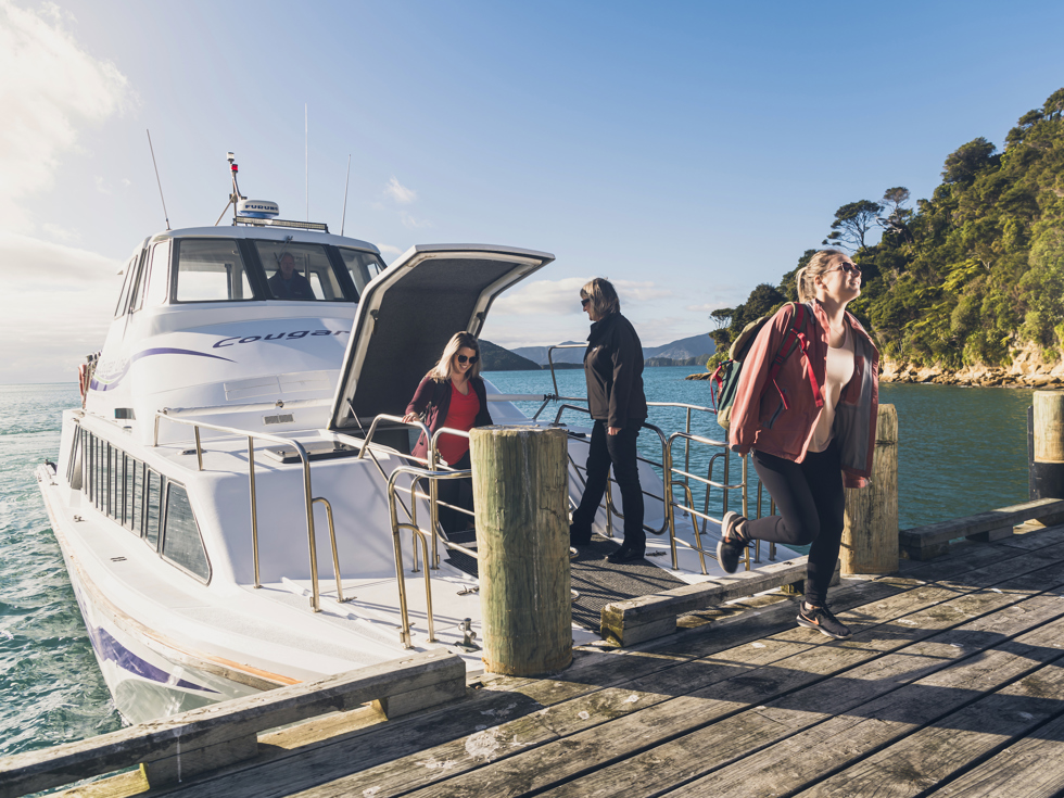 Cougar Line passengers disembark the boat at Ship Cove/Meretoto to start the Queen Charlotte Track in the Marlborough Sounds, New Zealand.