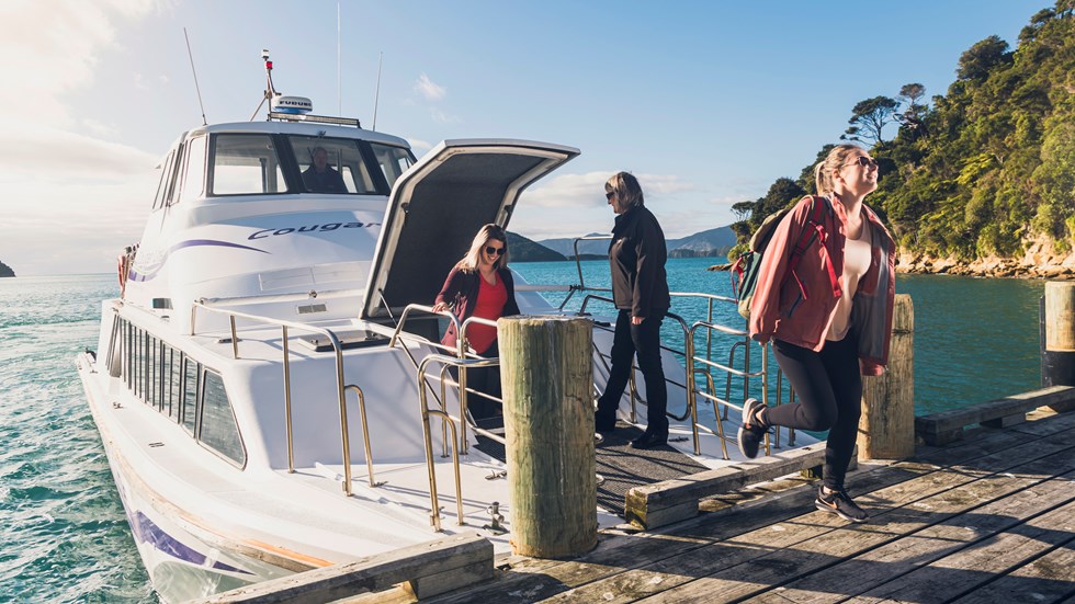 Cougar Line passengers disembark the boat at Ship Cove/Meretoto to start the Queen Charlotte Track in the Marlborough Sounds, New Zealand.